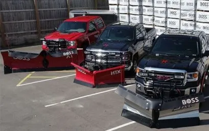 Three commercial trucks with BOSS snow plows installed in a parking lot at MTE's facility in Fishers, Indiana